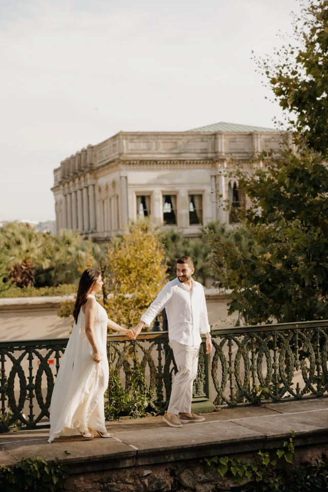 Natalie and Abdulrahman holding hands on a terrace in front of a palace