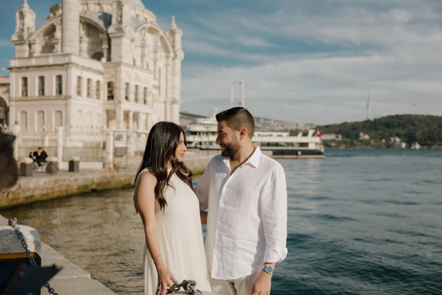 Natalie and Abdulrahman smiling at one another beside the water